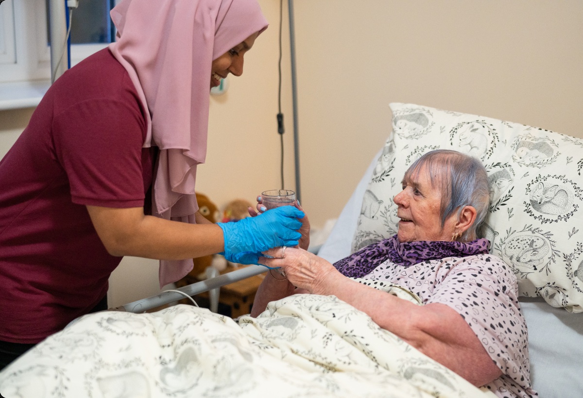 A caregiver providing care to a woman at home