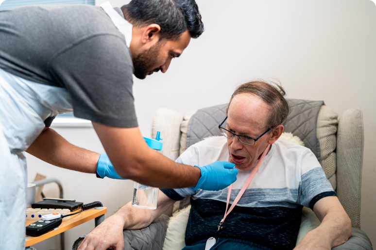 A care worker helping a man with a drink at home