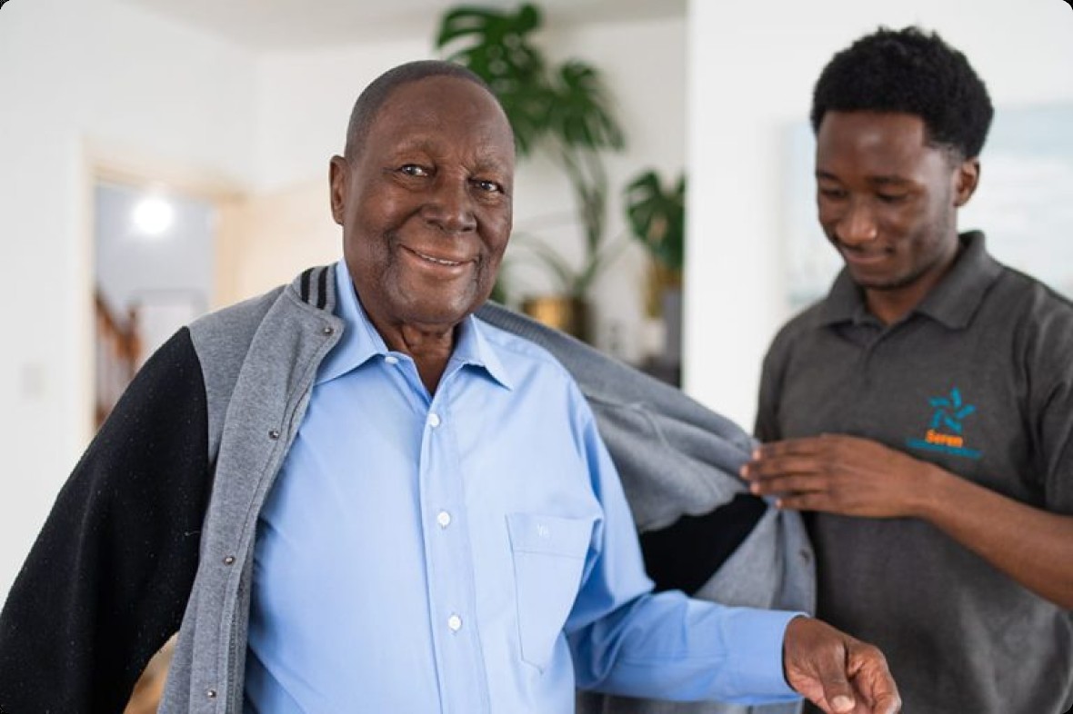 A Seren care professional helping a client with his cardigan