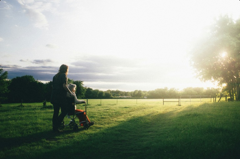 A care professional accompanying a wheelchair user outdoors